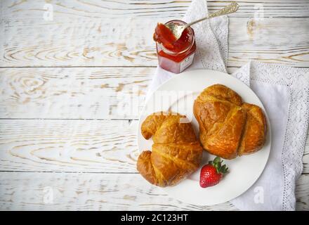 Two tasty croissants on the plate and strawberry jam Stock Photo