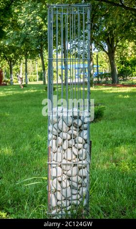 Stones in a metal cage as a decoration for a garden or park. Stock Photo