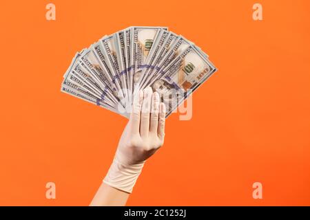 Profile side view closeup of human hand in white surgical gloves holding and showing fan of american dollar money in hand. indoor, studio shot, isolat Stock Photo