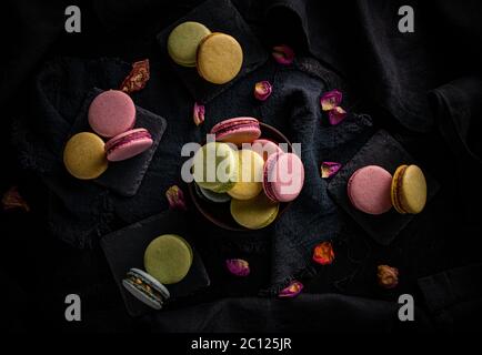 Flat lay of macaron cookies of different colors on black background Stock Photo