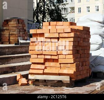 New bricks are stacked on a pallet and bags near the trade pavilion. Stock Photo