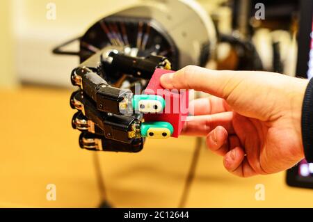 Man and Robot Hand Holding a Red Cube in Research Laboratory Stock Photo
