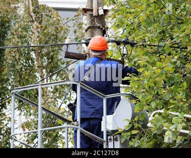 Electrical worker repairing the wires on the pole with the help of the lift car. Stock Photo