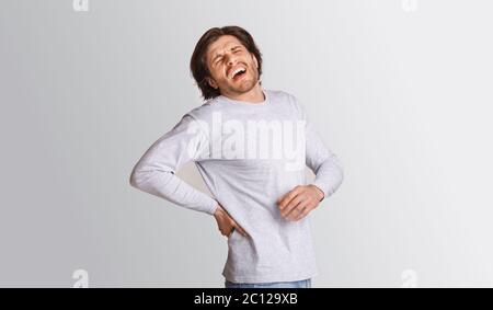 Sharp back pain. Man suffering from pain and screams Stock Photo