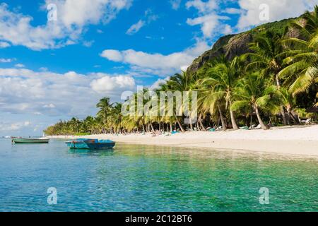 Tropical view of the resort on Mauritius. Ocean with boat, sandy beach with palms and sky Stock Photo
