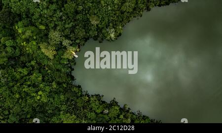 Aerial view on a lake surrounded by tropical amazon rainforest with a yellow boat and pier. Blue Laguna in San Martin region, Peru. Stock Photo