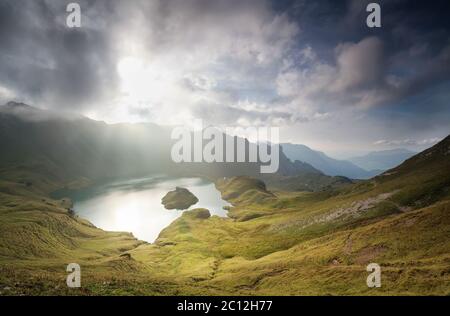 sunlight through clouds over alpine lake Stock Photo