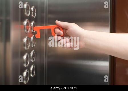 Young man using a contactless tool to press an elevator button, to avoid the spread of the coronavirus disease, Covid-19. New normal. Stock Photo