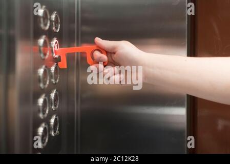 Young man using a contactless tool to press an elevator button, to avoid the spread of the coronavirus disease, Covid-19. New normal. Stock Photo