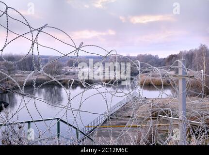 Post a fence of barbed wire in winter in frost at dawn Stock Photo