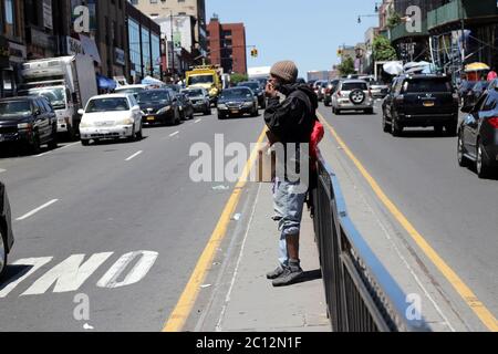 New York City, New York, USA. 13th June, 2020. On the first weekend of reopening in New York City under Phase 1 on 8 June, 2020, THE HUB, the main center of commerce in the Melrose section of the Bronx, was a hive of activities, with brisk street commerce and heavy pedestrian traffic on Saturday 13 June, 2020. Pictured is a homeless man enjoying a snack handed to him by a passing motorist. Credit: G. Ronald Lopez/ZUMA Wire/Alamy Live News Stock Photo