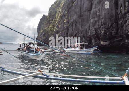 Tourists on traditional Philippino fisherman boats crossing the waters near limestone cliffs of El Nido at Palawan Island the Philippines Stock Photo