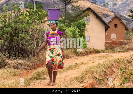 African Girl carries heavy basket on head. Madagascar Stock Photo