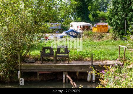 Two empty armchairs stand in the shade of an abandoned jetty Stock Photo