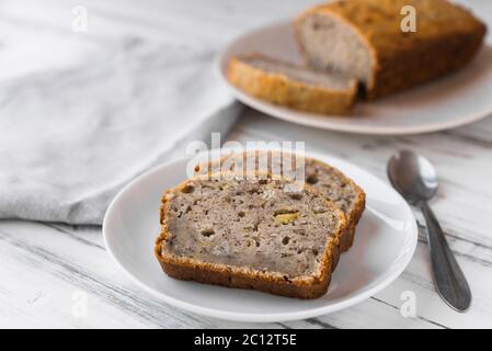 Vegan banana bread loaf cake against white wooden background. Stock Photo