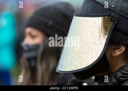 A supporter in a face shield braved heavy rains to attend the Statewide Silent March and General Strike at Judkins Park in Seattle's Central District neighborhood on Friday, June 12, 2020. Black Lives Matter Seattle-King County organized the statewide day of action and silent march to honor lives lost in support of all Black lives in Washington State. Stock Photo