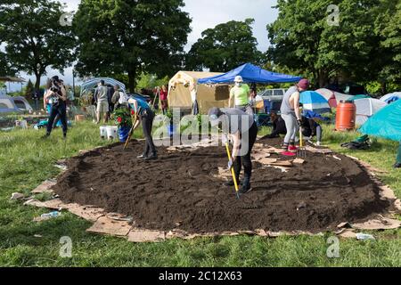 Protestors till soil to plant a garden in Cal Anderson Park in the “Capitol Hill Autonomous Zone” in Seattle on Friday, June 12, 2020. The zone, also known as CHAZ, is a self-declared intentional community and commune established when the Seattle Police Department closed the East Precinct after days of large protests and occasional violent clashes. Stock Photo