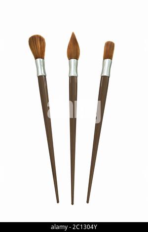Three paint brushes, round, pointed and square one, on white surface Stock Photo