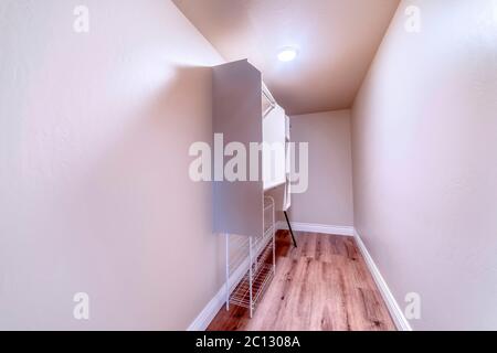 Walk in closet with metal rod and shelves on the wall mounted white cabinet Stock Photo