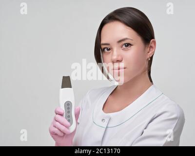Doctor taking ultrasonic cleaning device. Acian looking woman in uniform. Stock Photo