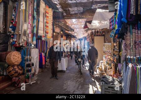 Souks, shoppers and tourists inside the medina with daylight streaming in in Marrakech, Morocco Stock Photo