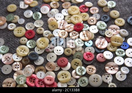 Image of a bunch of buttons of different shapes, colors and sizes scattered on a gray surface Stock Photo