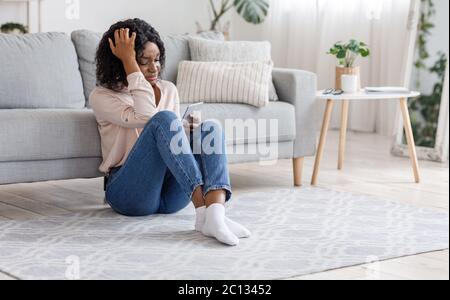 Heartbroken Girl. Crying Black Woman Sitting With Smartphone On Floor At Home