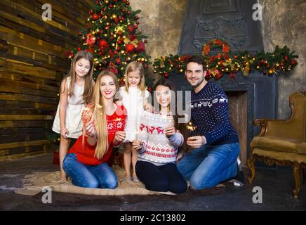 Young family near fireplace celebrating Christmas Stock Photo