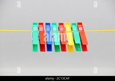 colored plastic clothespins hanging on the rope. Stock Photo