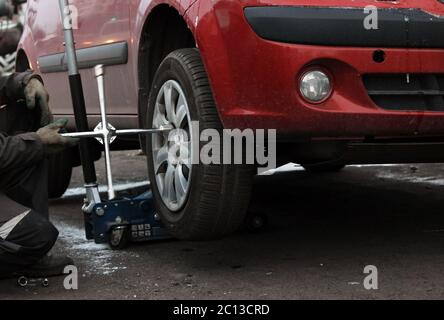 installation of passenger car wheel and replacement on winter tire. Stock Photo