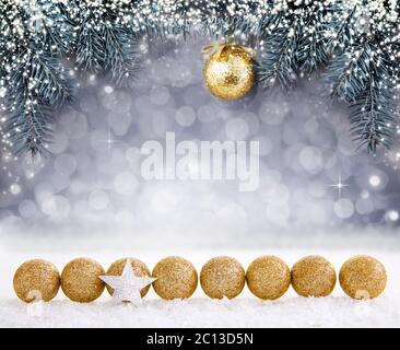 Christmas background with snow and golden ball on spruce branch. Stock Photo