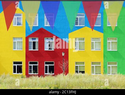 Multi Colored Triangular Flags Hanging in the Sky at an Outdoor against the backdrop of colorful houses. Stock Photo