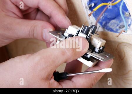 Worker man electrician is repairing damaged sockets in the apartment, installation of new closeup Stock Photo