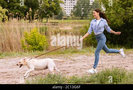 Excited girl and retriever running in countryside Stock Photo