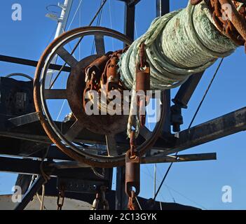 Detailed closeup of rusty old winch and rope on a fishing trawler boat. Stock Photo