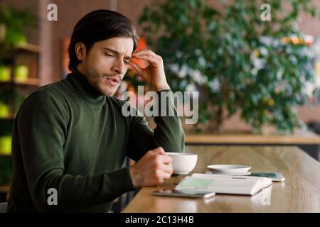 Depressed man having problems with job, drinking coffee at cafe Stock Photo