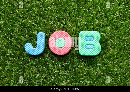 Toy foam letter in word job on green grass background Stock Photo