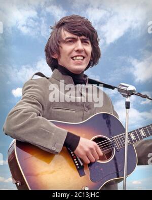 George Harrison performs “I Need You” on the movie set of HELP! Filmed on Salisbury Plain, Wiltshire. May 4, 1964. Stock Photo