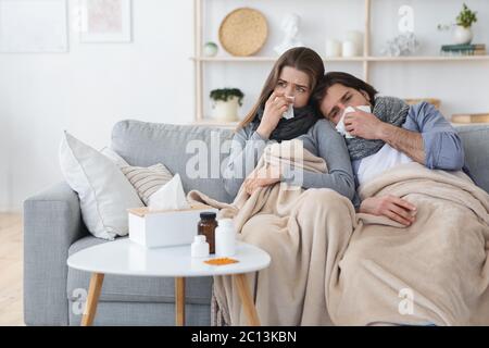 Couple Suffering From Cold, Blowing Noses And Sneezing Stock Photo