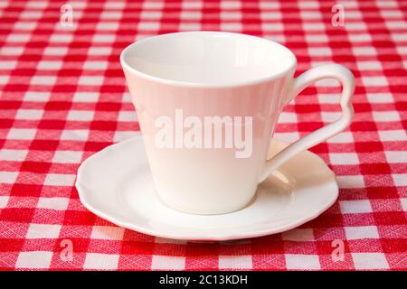 White cup on the checkered tablecloth Stock Photo