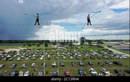 June 13, 2020 - Sarasota, Florida, United States - In this aerial view from a drone, high wire artists Nik Wallenda (right) and Blake Wallenda perform at Nik Wallenda's Daredevil Rally, billed as the world's first drive-in stunt show, on June 13, 2020 in Sarasota, Florida. The show, which runs on select dates through June 21, features internationally known daredevil performers and is designed to be a safe event during the coronavirus pandemic, with the separation of spectator's vehicles according to social distancing guidelines. (Paul Hennessy/Alamy) Stock Photo