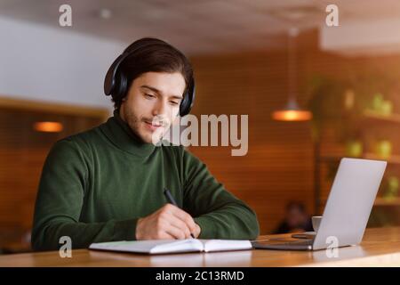 Concentrated guy with headset studying online, using laptop Stock Photo
