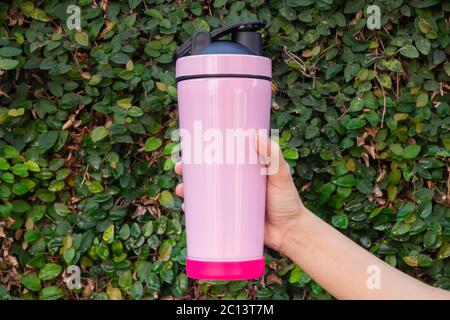 Aluminum thermos mug on hand with green leaves wall, stock photo Stock Photo