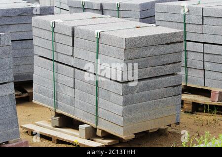 many curbs for construction works on pallets at the  site  laying paving slabs  city square. Stock Photo