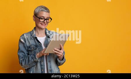 Modern Technologies For Leisure. Stylish Mature Lady Reading News On Digital Tablet Stock Photo
