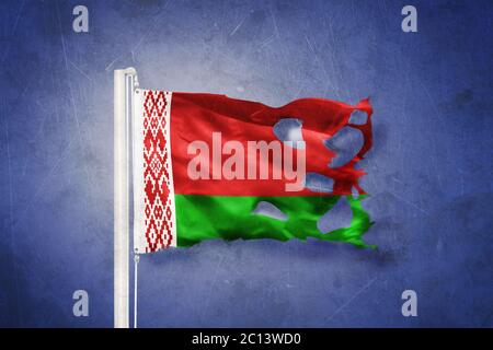 Torn flag of Belarus flying against grunge background Stock Photo