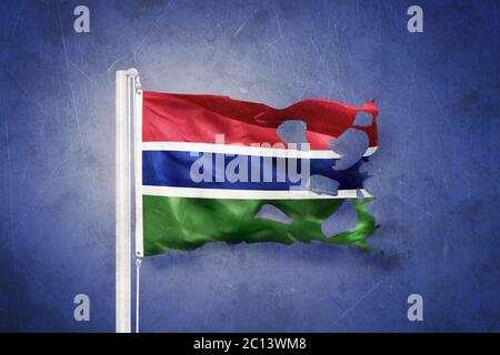 Torn flag of Gambia flying against grunge background Stock Photo