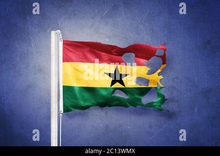 Torn flag of Ghana flying against grunge background Stock Photo