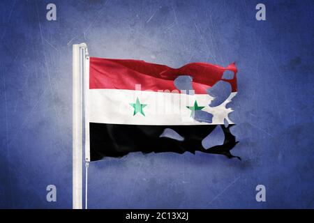 Torn flag of Syria flying against grunge background Stock Photo