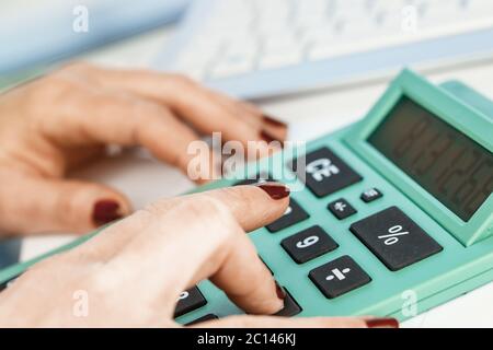 Close-up portrait of red nails businesswoman hand while using calculator. Stock Photo
